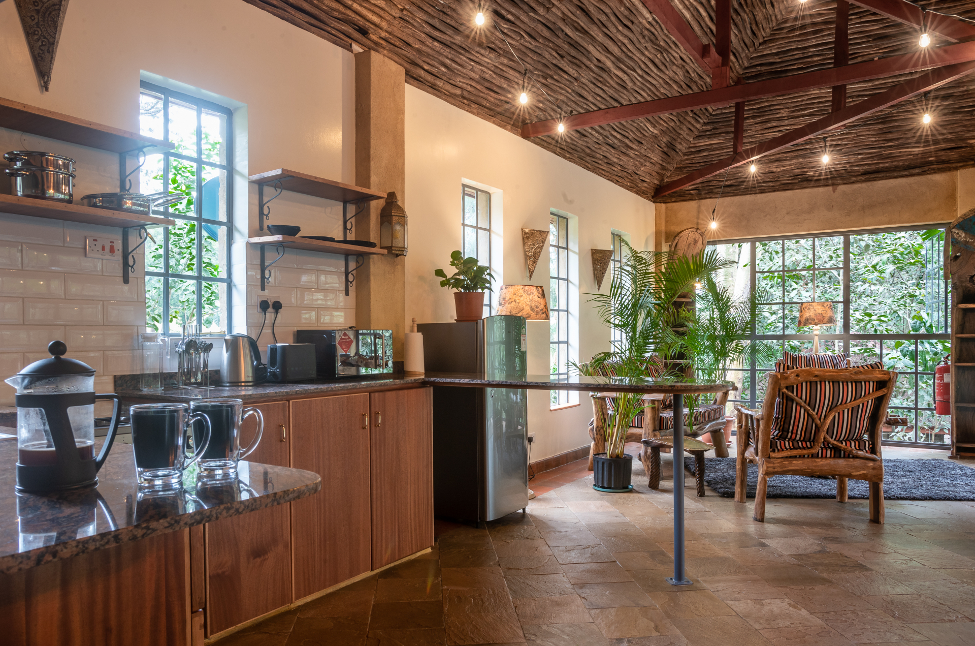 In-suite kitchenette with granite worktops, timber cabinetry and a woven-branch vaulted ceiling