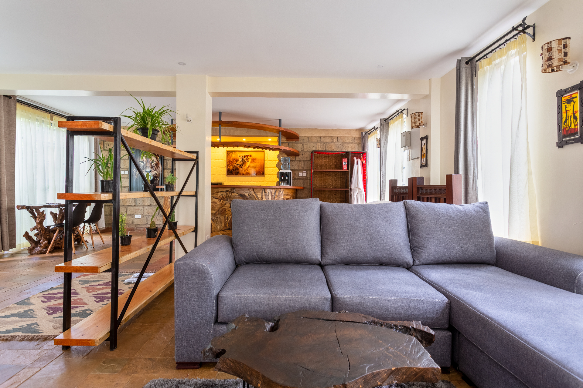 Grey sectional sofa and timber divider looking back toward the dining nook, kitchenette bar and wardrobe area