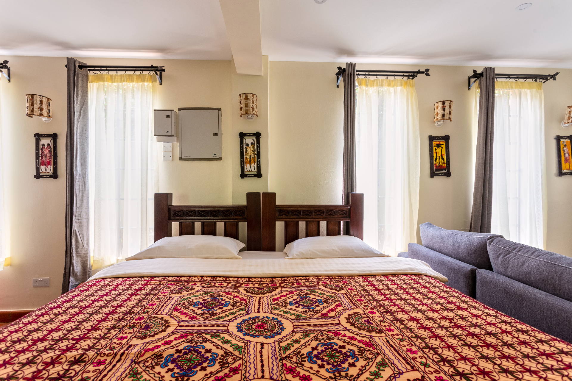 Head-on view of the studio bed set against a wall of tall curtained windows beside the lounge sofa