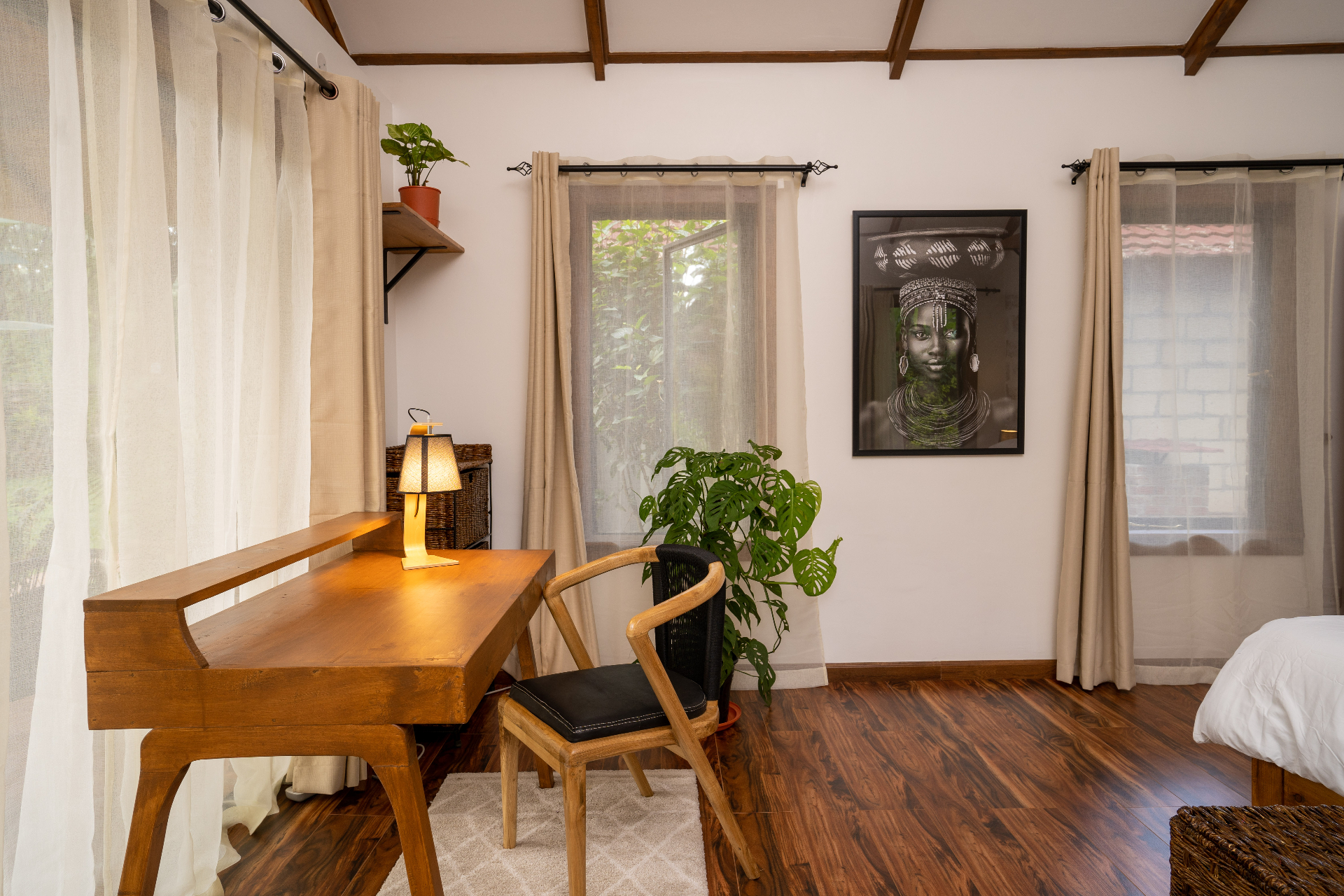 Closer angle of the Cottage 2 writing desk with warm lamp glow, timber chair, soft curtains and framed portrait against the bedroom wall