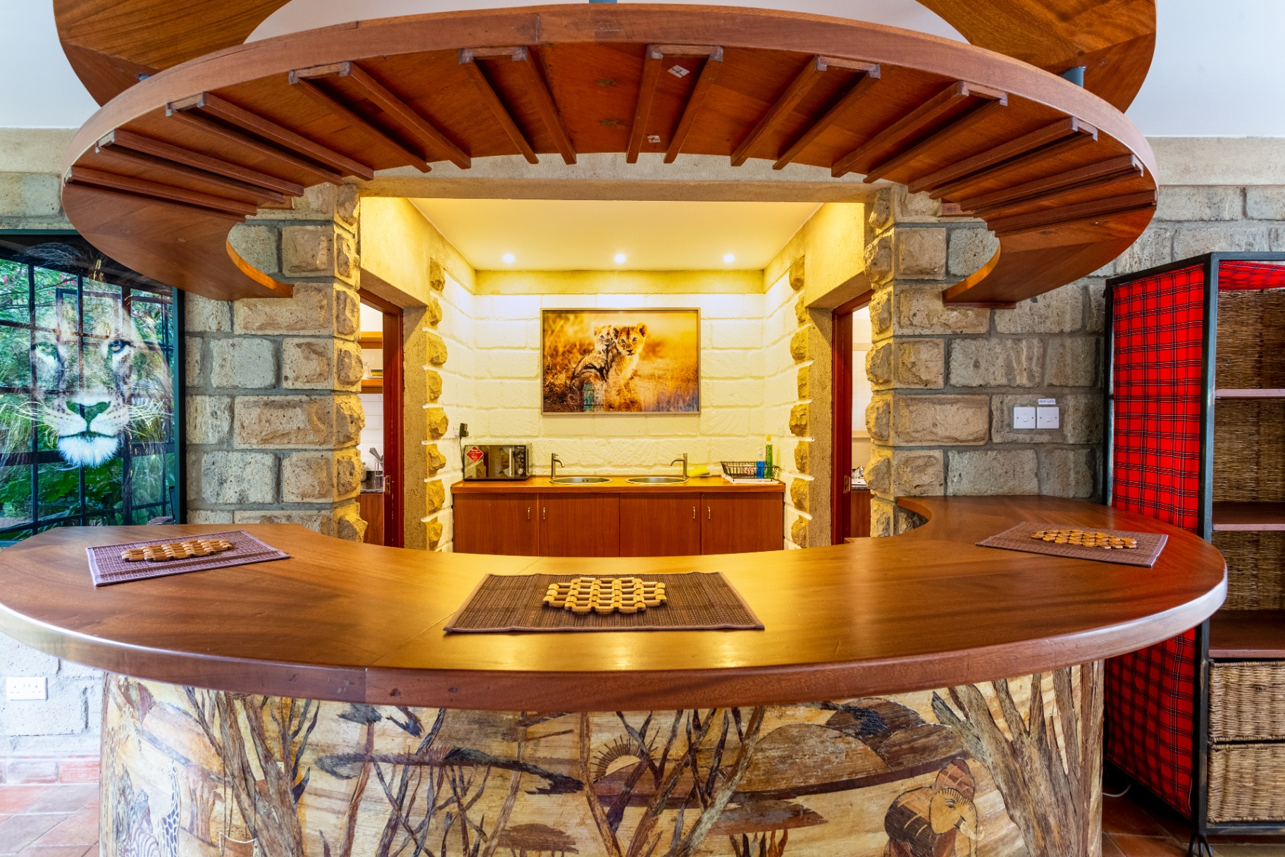 View through the curved timber bar arch toward the kitchenette with lion cub artwork and warm ambient lighting