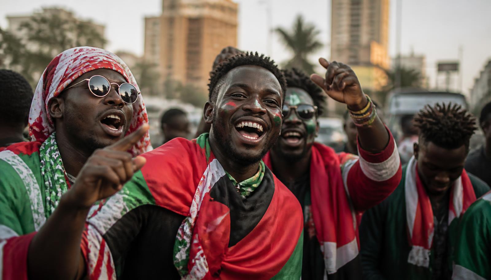 Football supporters draped in flags celebrating in a city street ahead of AFCON 2027 matches