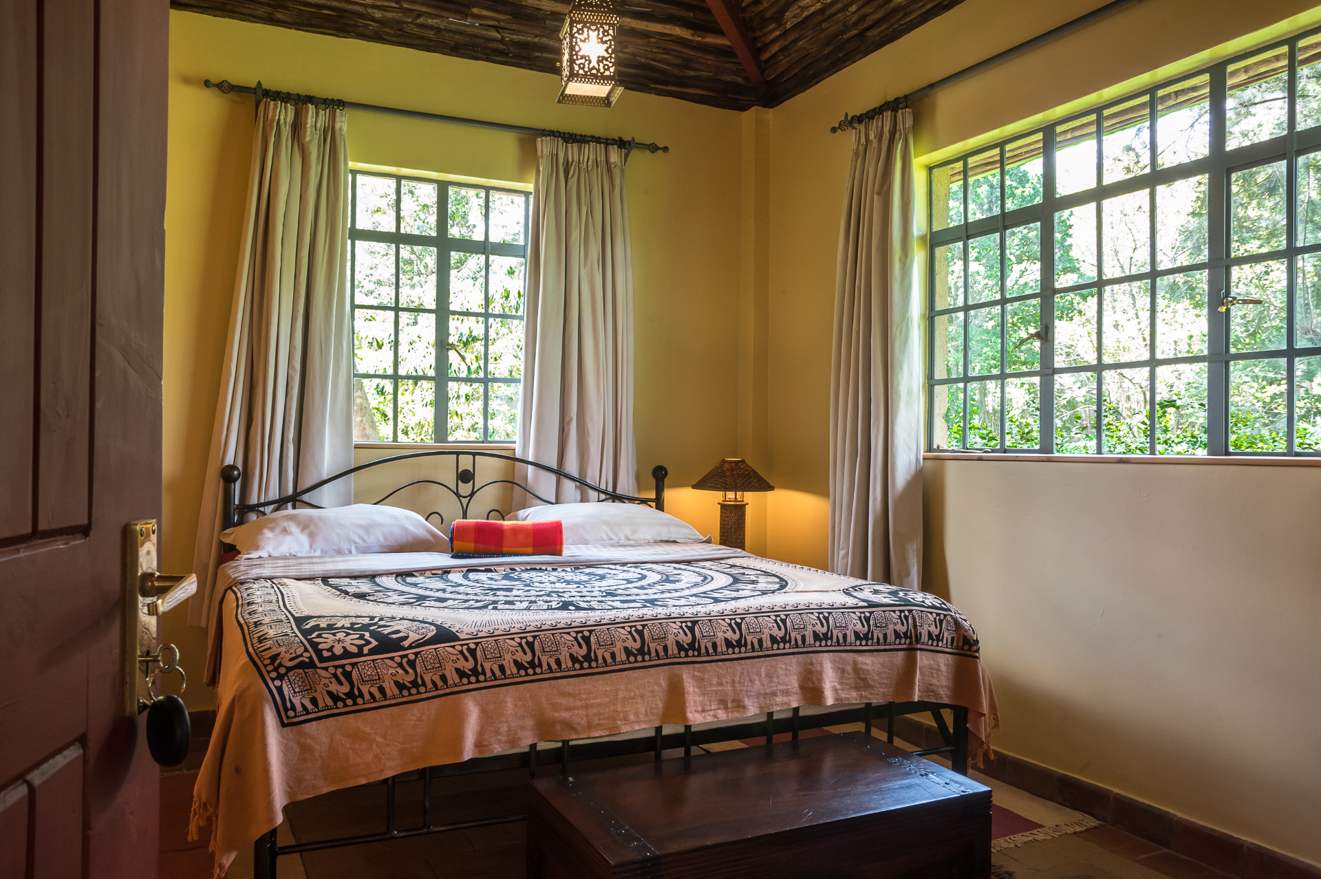 View from the entry into the bedroom with a white bathrobe hanging nearby and a patterned rug under the bed